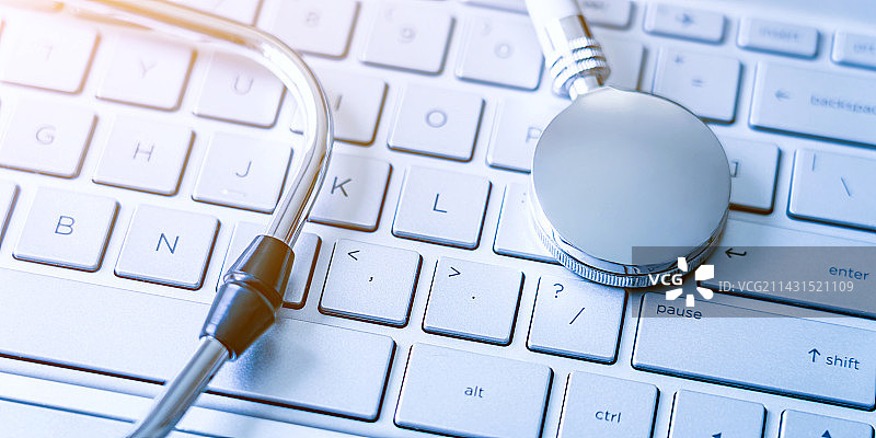 听诊器放在银色电脑键盘上——健康医疗概念图片素材