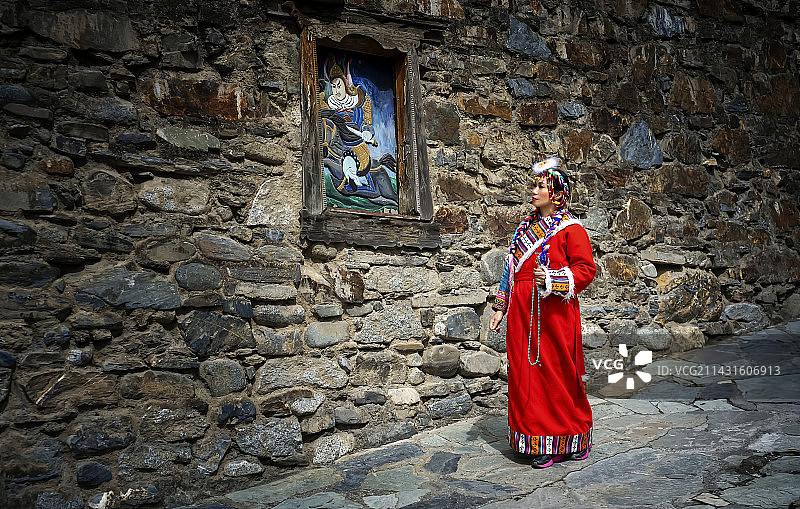 穿着藏族服装的妇女手里拿着佛珠走在阿坝州甘堡藏寨的一条小巷里图片素材