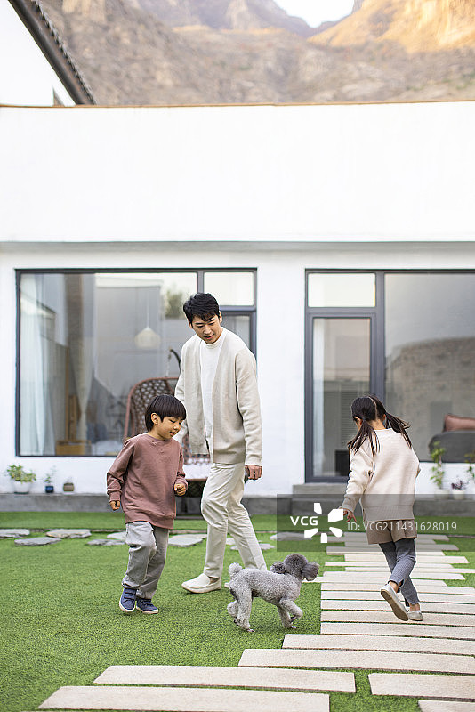 快乐的年轻家庭和宠物狗在庭院里玩耍图片素材