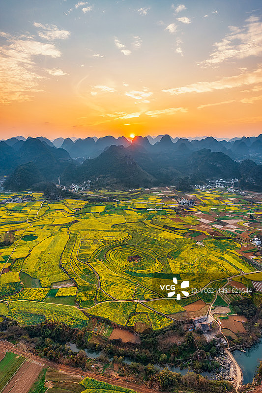 贵州省黔西南布依族苗族自治州兴义市万峰林景区油菜花田（万峰林八卦田）春季户外日落风光航拍视角图片素材