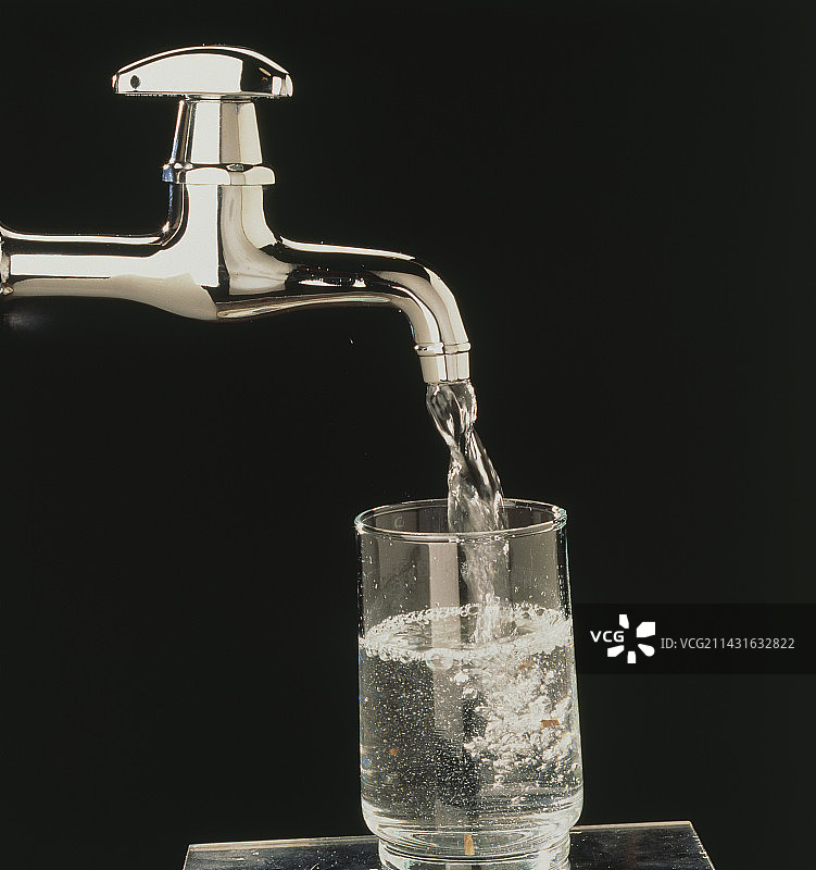家用自来水龙头将饮用水倒入玻璃杯中图片素材