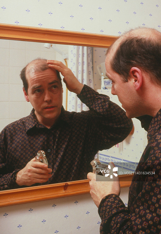 秃顶男子在头皮上涂抹乳液图片素材