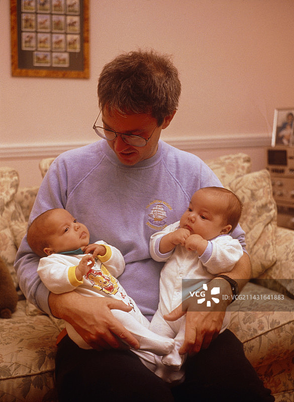父亲抱着婴儿同卵双胞胎图片素材