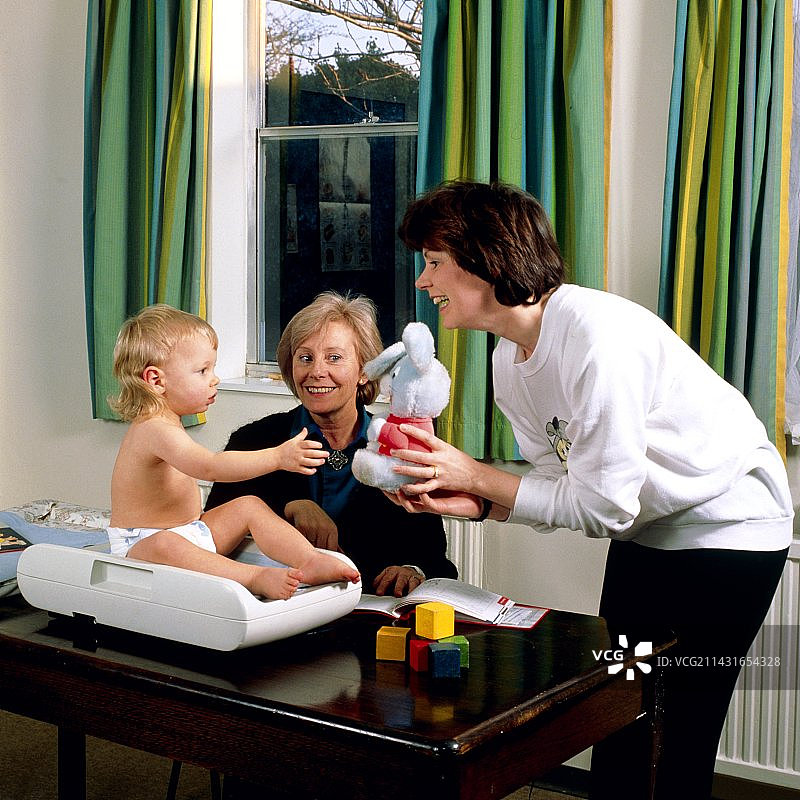 在诊所称量 18 个月大的婴儿。图片素材