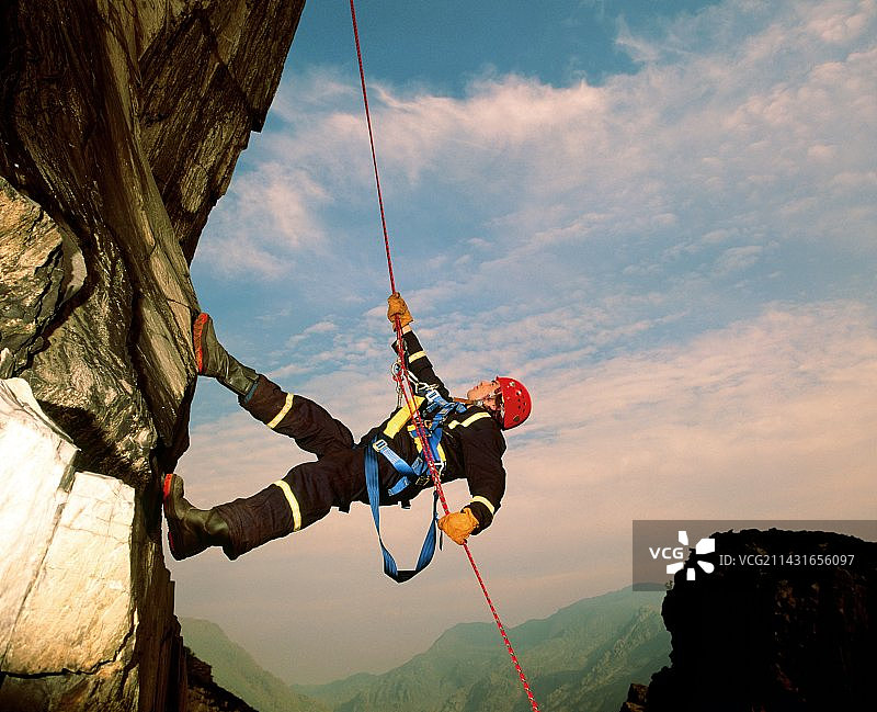 攀岩者在岩壁上绳降图片素材