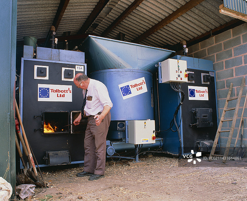 农民照料木片燃烧设备图片素材