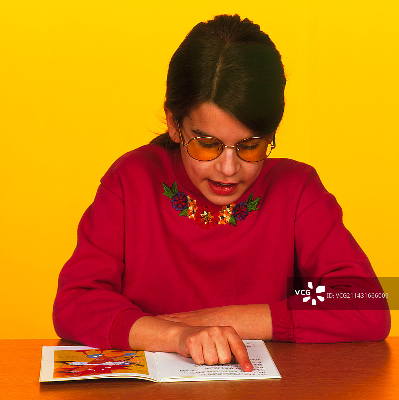 戴着Irlen镜片阅读的阅读障碍女孩图片素材
