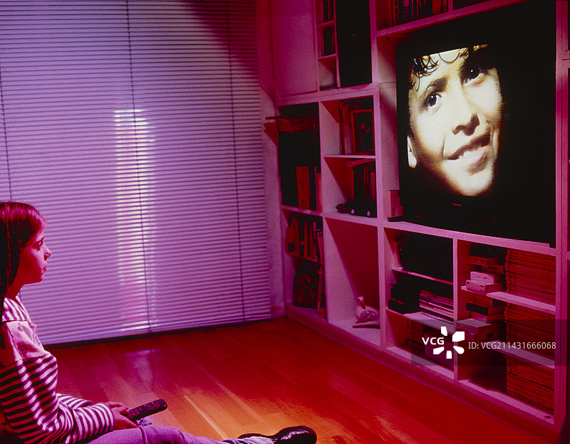 女孩使用遥控器看电视图片素材