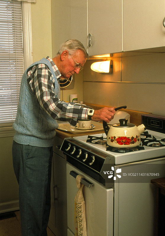 老年男人佩戴着紧急设备做饭图片素材