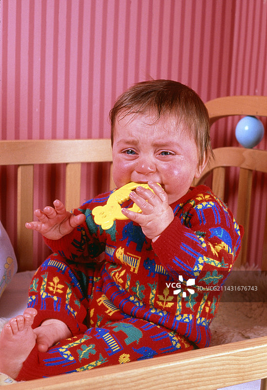 八个月大的男孩在婴儿床里哭泣图片素材