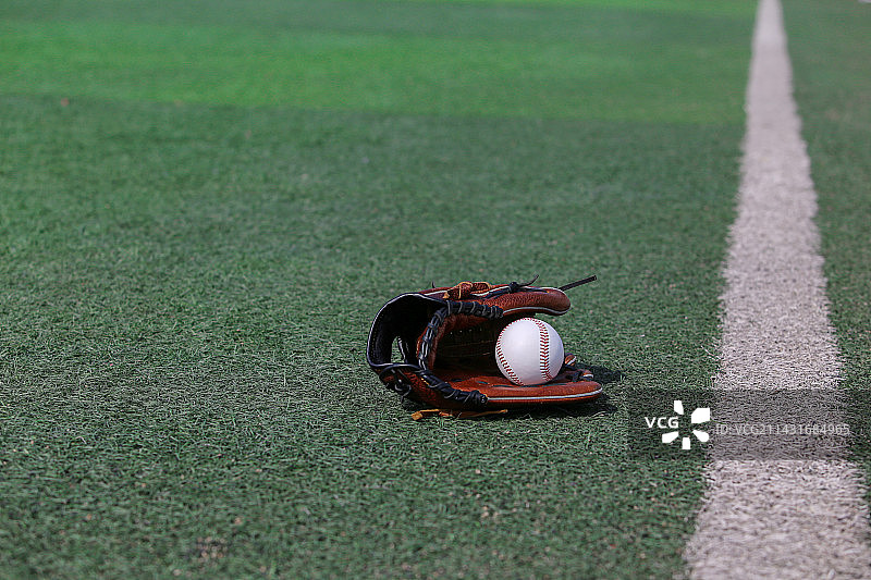 球场绿色草地上的棒球和手套图片素材