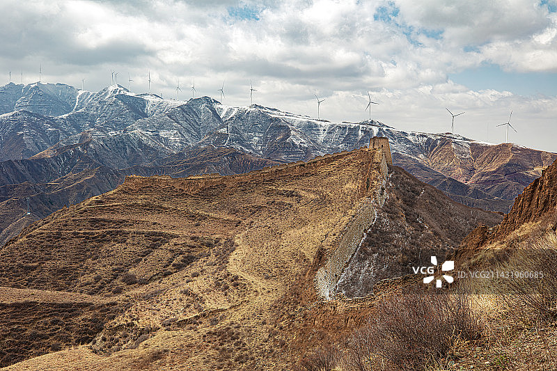 山西朔州忻州交界黄土高坡白草口长城，蜿蜒长城沿山势拐弯，垛口分明烽火台制高点，背景为积雪山脉图片素材
