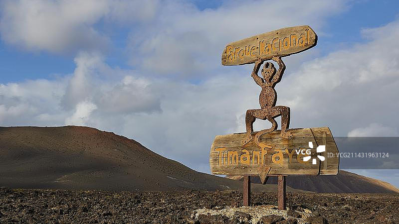 蒂曼法亚国家公园入口处的木制雕塑和标志，火山景观，蓝天白云，兰萨罗特岛，加那利群岛，西班牙，欧洲图片素材