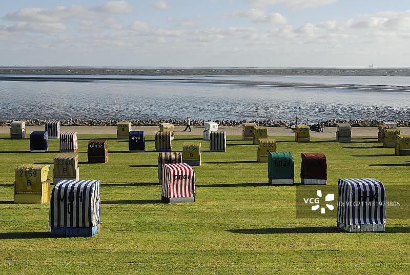 草坪上的带顶棚柳条沙滩椅，位于德国石勒苏益格-荷尔斯泰因州迪特马尔申的比苏姆，北海瓦登海图片素材