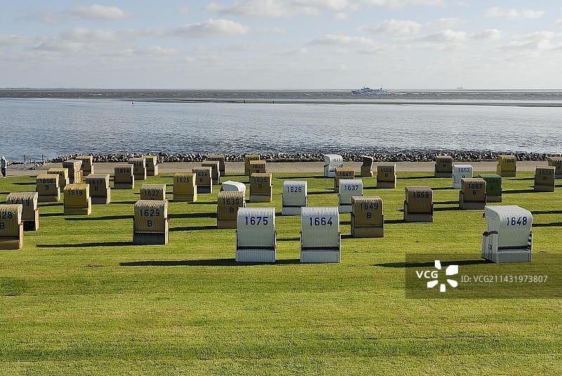 草坪上的带顶棚柳条沙滩椅，位于德国石勒苏益格-荷尔斯泰因州迪特马尔申的比苏姆，北海瓦登海图片素材