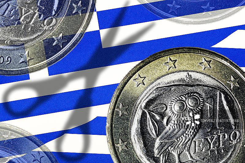 希腊欧元硬币和希腊国旗上的一把剪刀的阴影，象征着希腊的债务削减图片素材