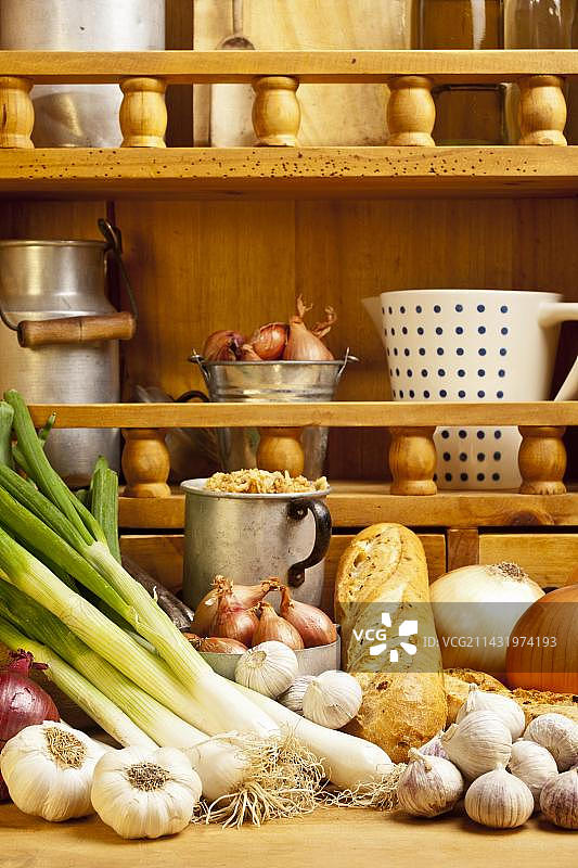 不同类型的洋葱和大蒜，以及洋葱面包，背景是带有香料的架子图片素材