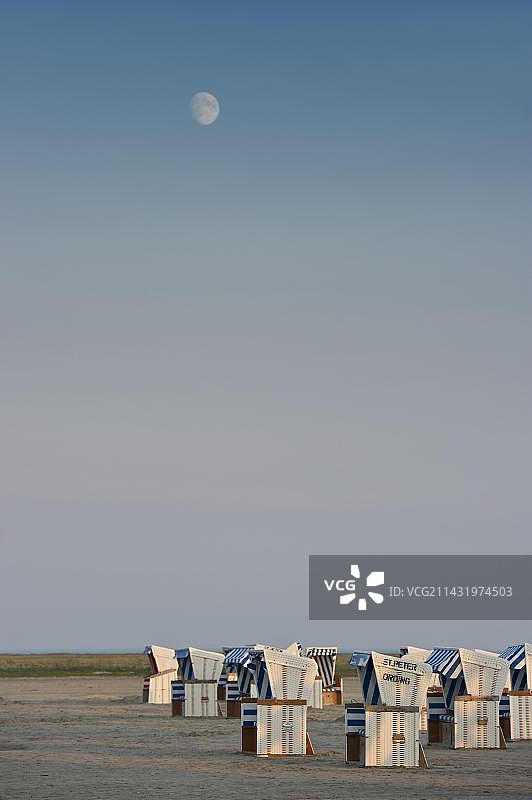 德国圣彼得奥尔丁海滩上空的月亮与带顶棚的柳条沙滩椅图片素材