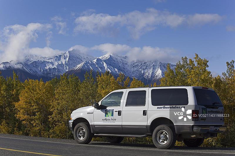SUV行驶在阿拉斯加高速公路上，秋季树木，圣埃利亚斯山脉，克卢恩国家公园和保护区，加拿大育空地区，北美图片素材