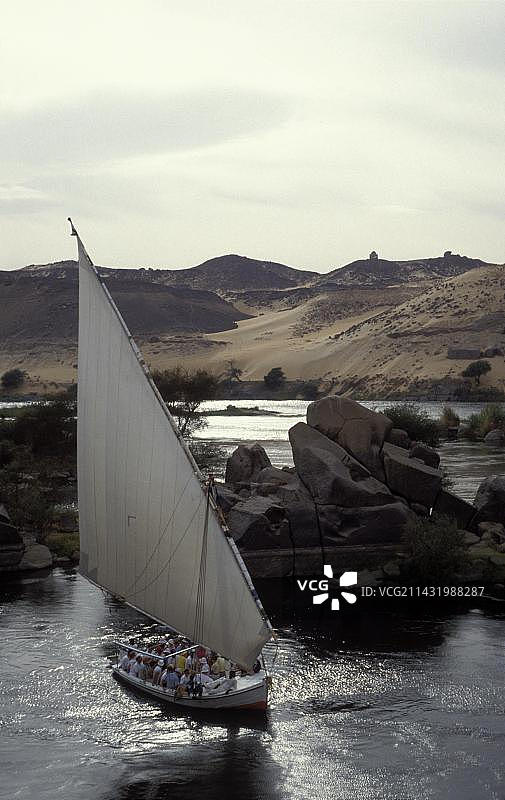 尼罗河上的三角帆船与游客，位于埃及阿斯旺附近的撒哈拉沙漠前，北非，非洲图片素材