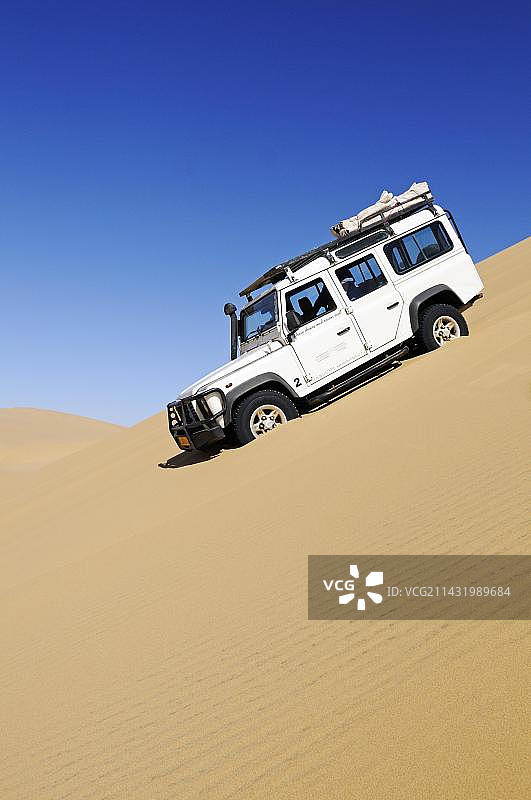 路虎卫士越野车行驶在纳米比亚纳米布-诺克卢夫国家公园的沙丘上图片素材