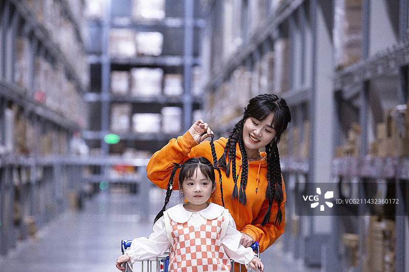 年轻妈妈推着女儿一起逛超市图片素材