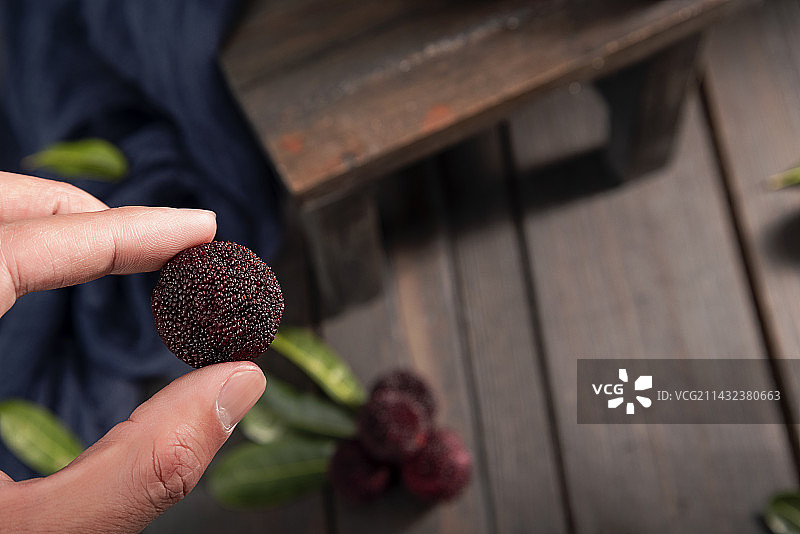 手拿杨梅木桌背景图片素材