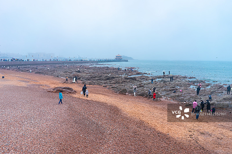 中国青岛旅游城市拍摄主题，栈桥蓝天白云飞翔的海鸥和海洋海岸上的礁石沙滩游客，户外白昼无人图像摄影图片素材