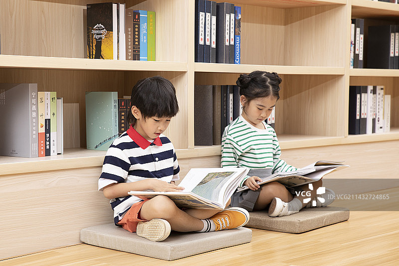 坐在地板上一起看画册的小朋友图片素材