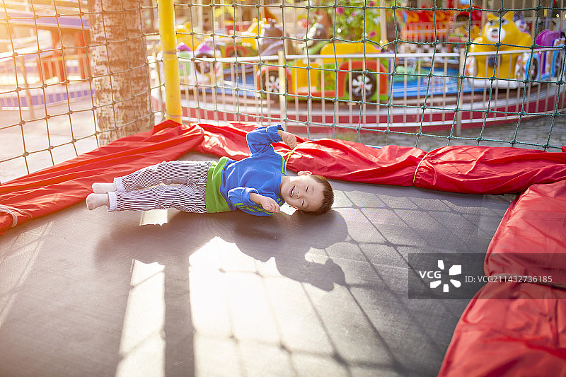 可爱的男孩躺在蹦蹦床上玩耍图片素材