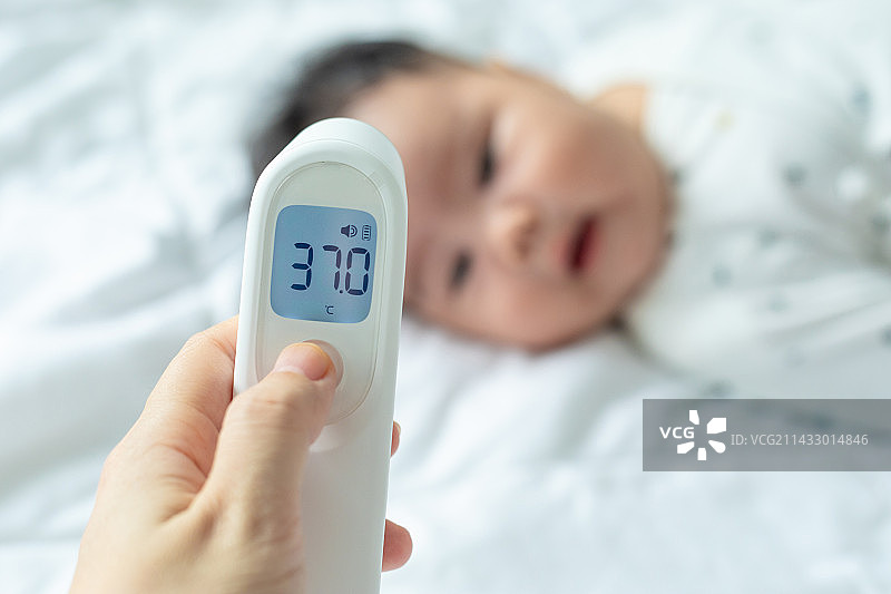 妈妈使用额温枪给婴儿量体温图片素材