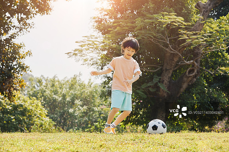 逆光下踢足球的小男孩图片素材