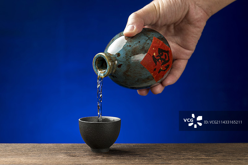 男人手拿酒壶倒酒特写深色调图片素材