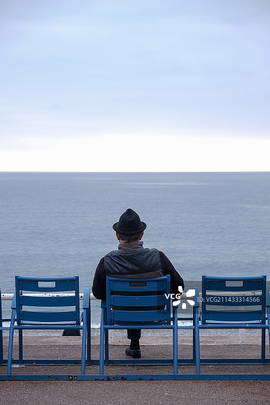 坐在长椅上看海的人的后视图图片素材