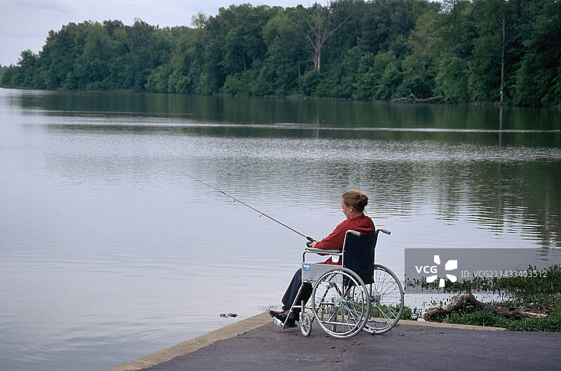 坐在轮椅上在阿肯色河钓鱼的女人图片素材