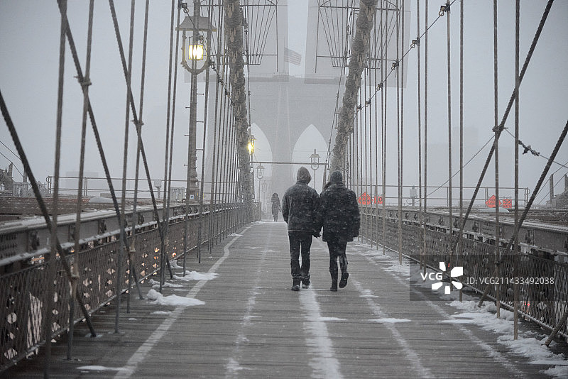 暴风雪期间空无一人的布鲁克林大桥上的两个人图片素材