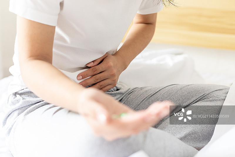 卧室里一名腹痛的年轻女性图片素材