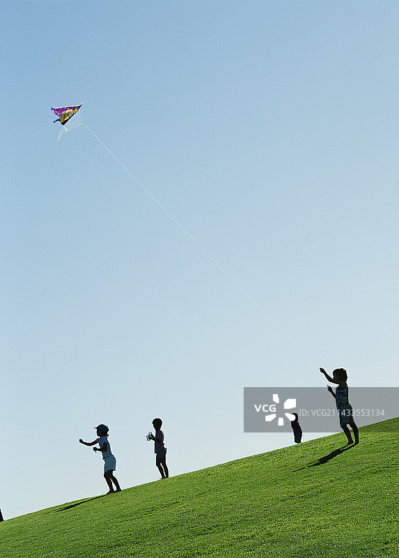 孩子们在晴朗的天空下放风筝图片素材