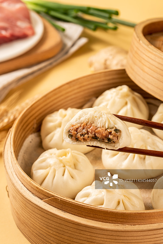 木板背景上一盘美味肉包子图片素材