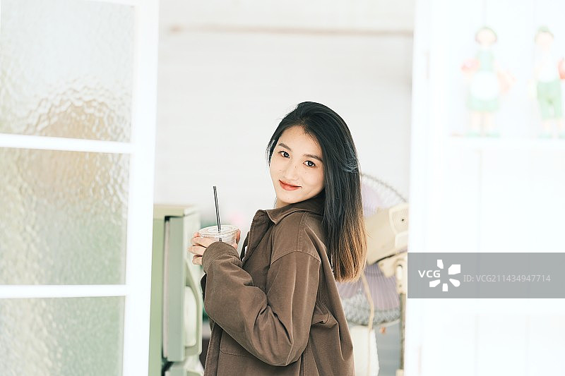 站在窗边拿着饮料的年轻女子图片素材