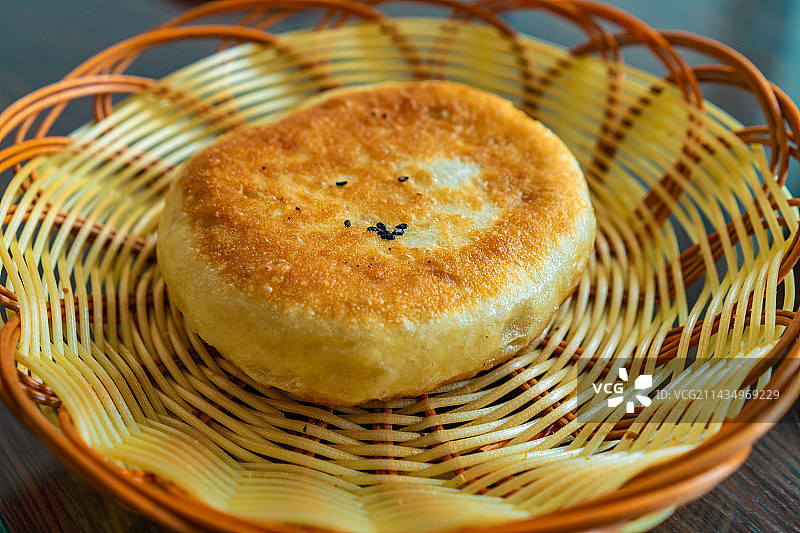 中国传统饮食产品拍摄主题，一个篮子里装着一个金黄色的牛肉饼，户外白昼无人图像摄影图片素材