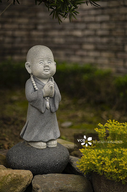 户外墙边一个可爱的小沙弥雕像图片素材