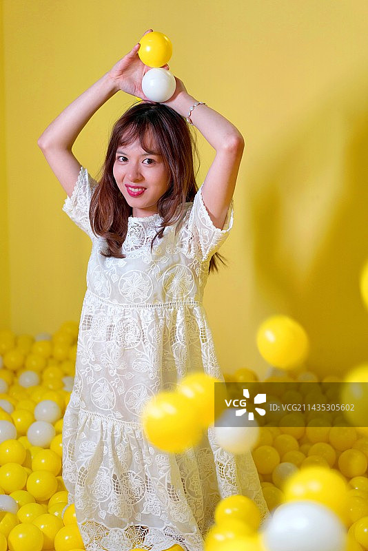 站在黄色背景下拿着气球的女孩图片素材