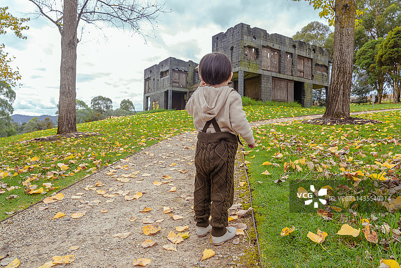 山坡破旧建筑物前小道上的小男孩图片素材