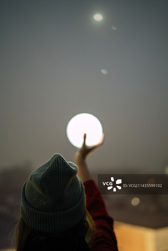 西班牙夜景：女子手持发光球的背影图片素材