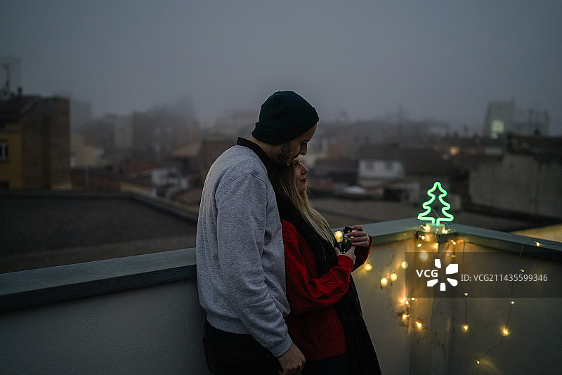 情侣在西班牙黄昏时分手持灯光，背靠天空图片素材