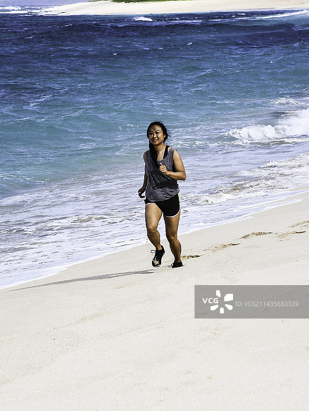 在美国夏威夷哈雷瓦海滩跑步的女人全身照图片素材