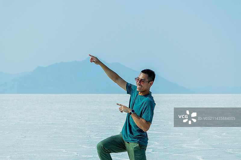 站在白色沙滩上，以晴朗天空为背景的年轻男子肖像，美国犹他州博纳维尔盐滩图片素材