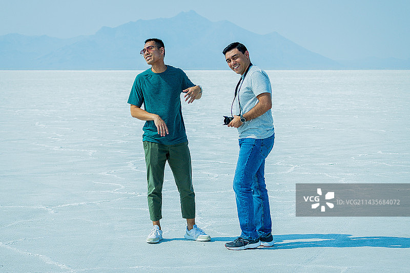 站在白色沙滩上，以晴朗天空为背景的年轻男子肖像，美国犹他州博纳维尔盐滩图片素材