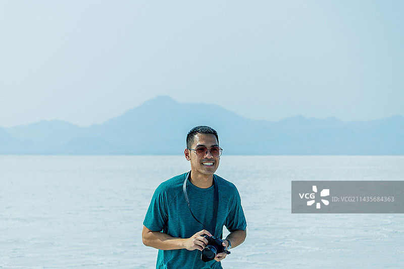 男子站在犹他州博纳维尔盐滩海滩上手持相机的人像照片图片素材